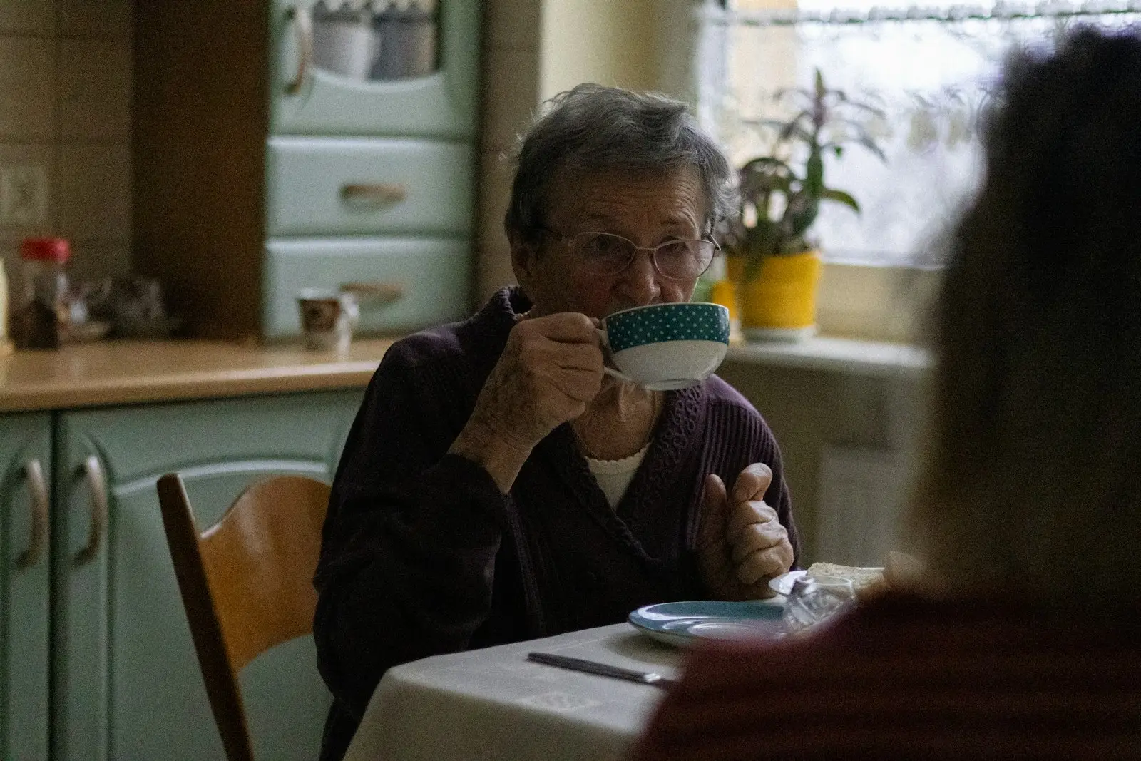 Ältere Frau trinkt Kaffee an ihrem Küchentisch – Unterstützung im Haushalt und Alltag