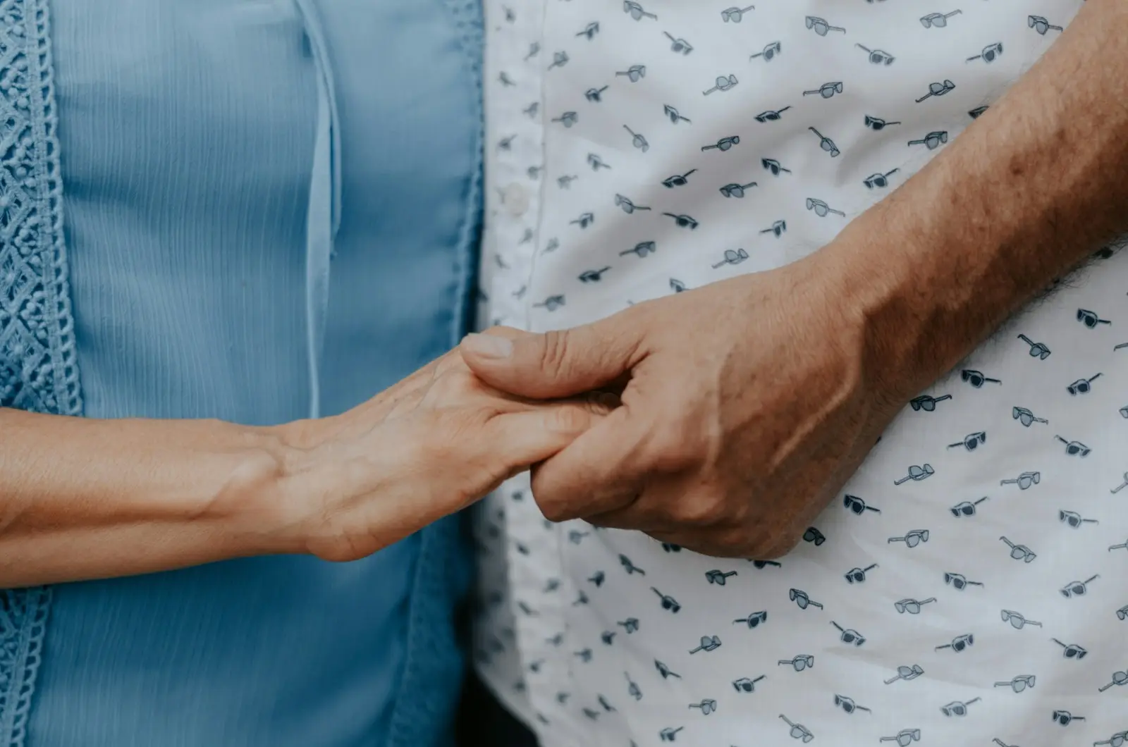Eine ältere und eine jüngere Hand halten einander – familiäre Pflege ist Vertrauenssache